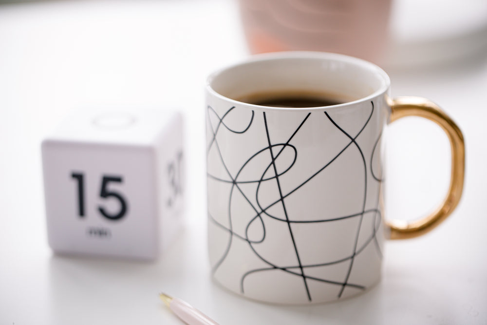 close up white mug filled with coffee on a desk