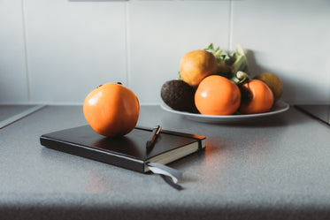closed notebook with a pen and a persimmon on top of it