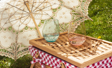 cloth parasol lays on the grass next to a picnic basket