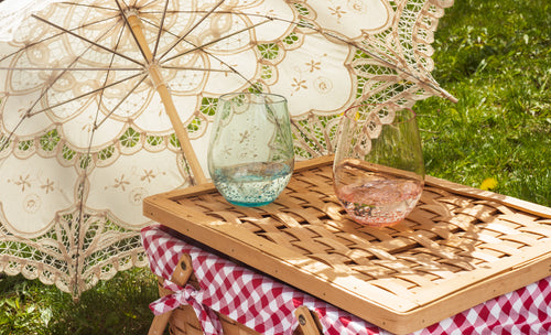 cloth parasol lays on the grass next to a picnic basket