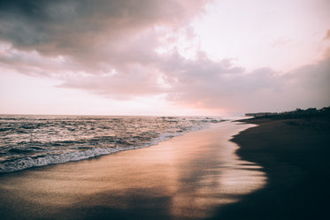 clouds in a pink sky over wave-soaked beach