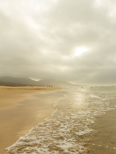 cloudy sky covers the beach as people walk by