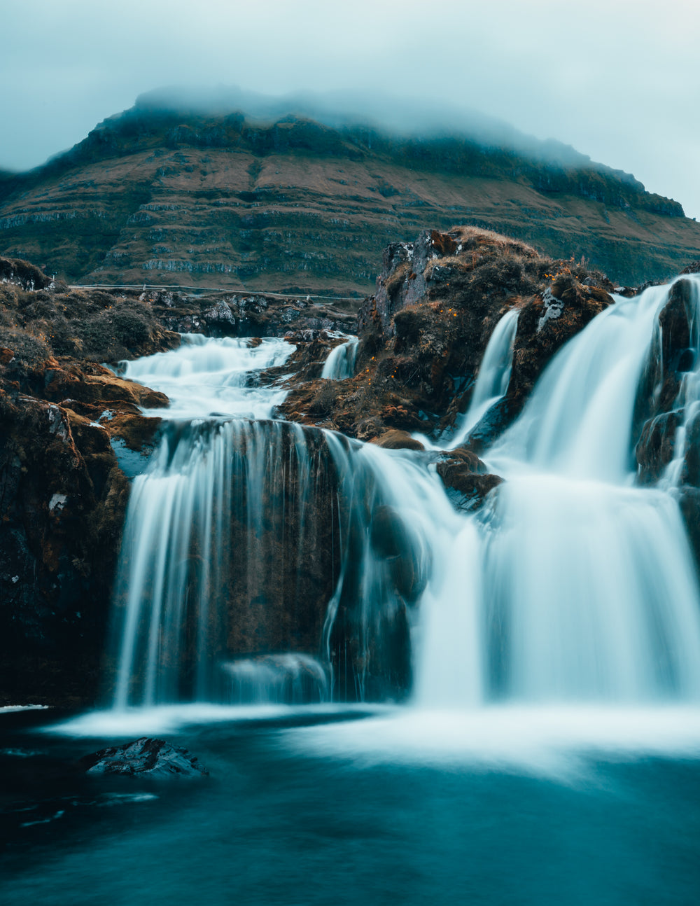 cloudy waterfall at the base of a mountain