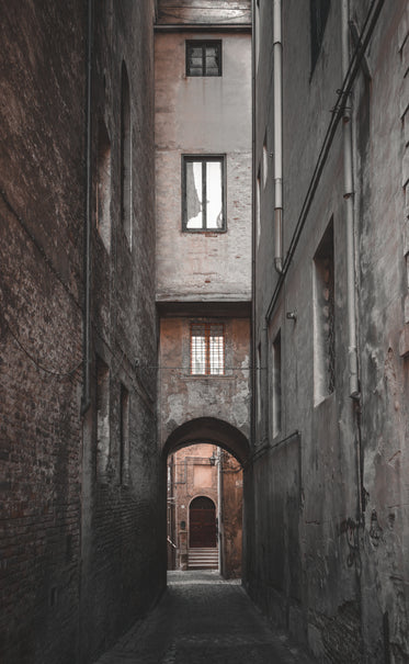 cobblestone alley leading to archway at the end