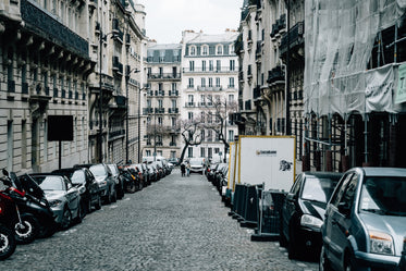 cobblestone street with tall buildings and cars