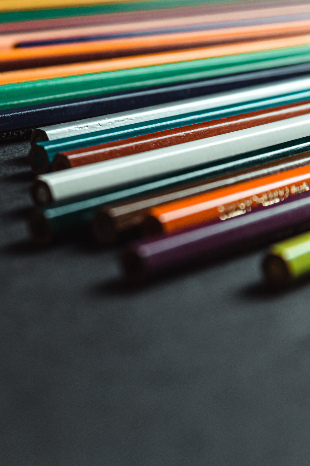 colored pencils lines up on a black background