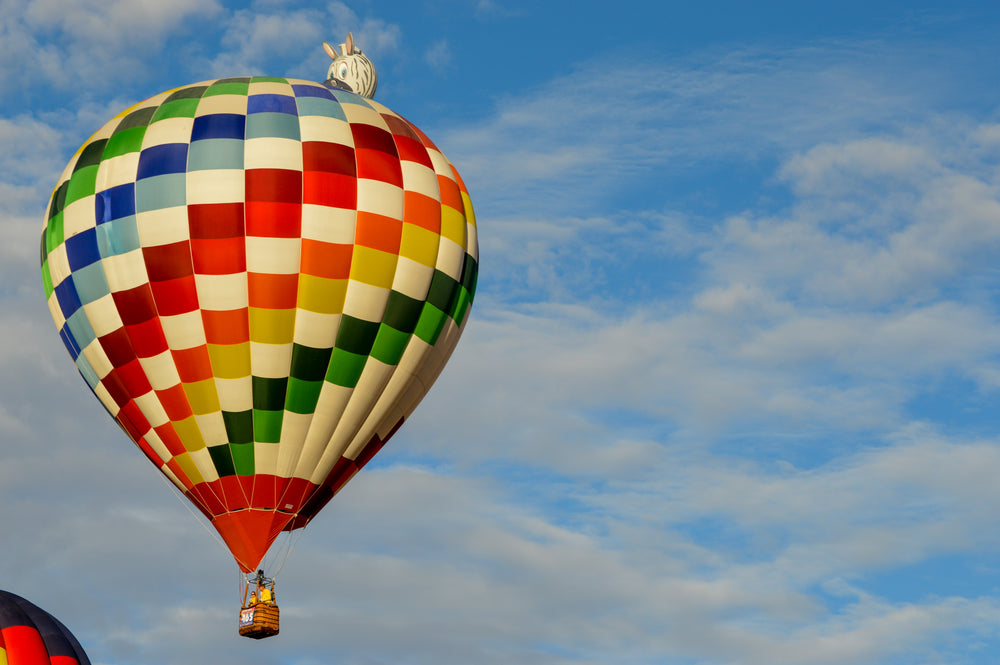 colorful hot air balloon flies against a blue sky