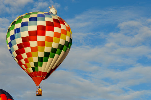 colorful hot air balloon flies against a blue sky