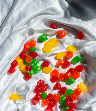 colorful jube jubes lay in the folds of a white silk sheet