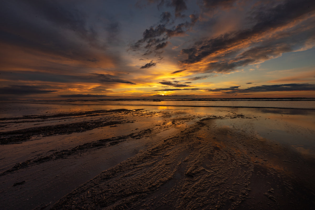 色彩斑斓的日落倒映在富有质感的沙滩上
