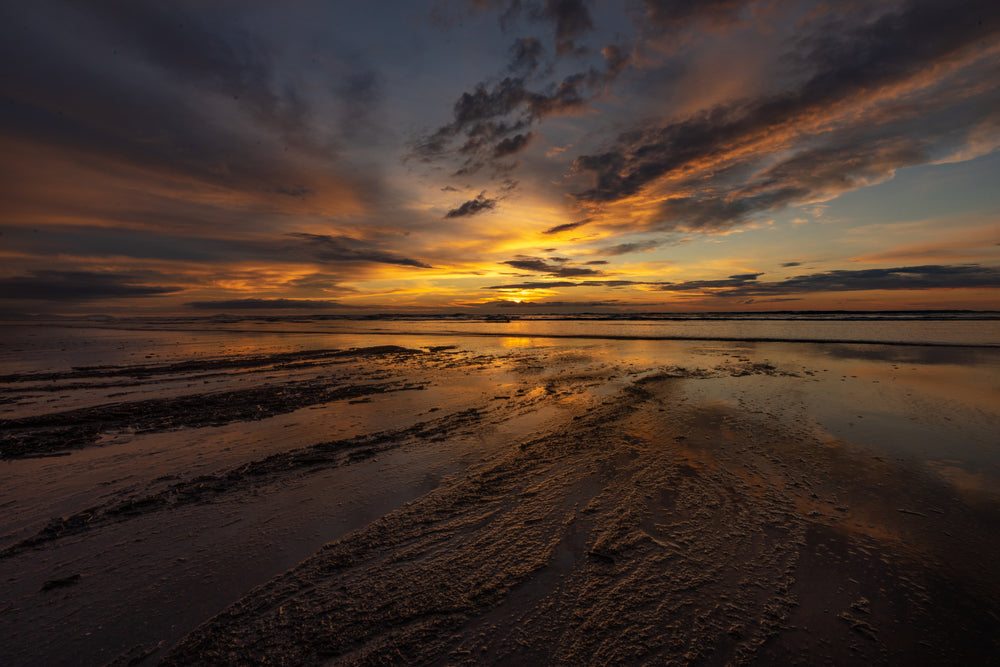 colorful sunset reflected in textured beach sand