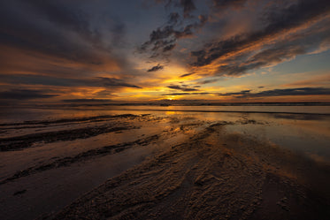 colorful sunset reflected in textured beach sand