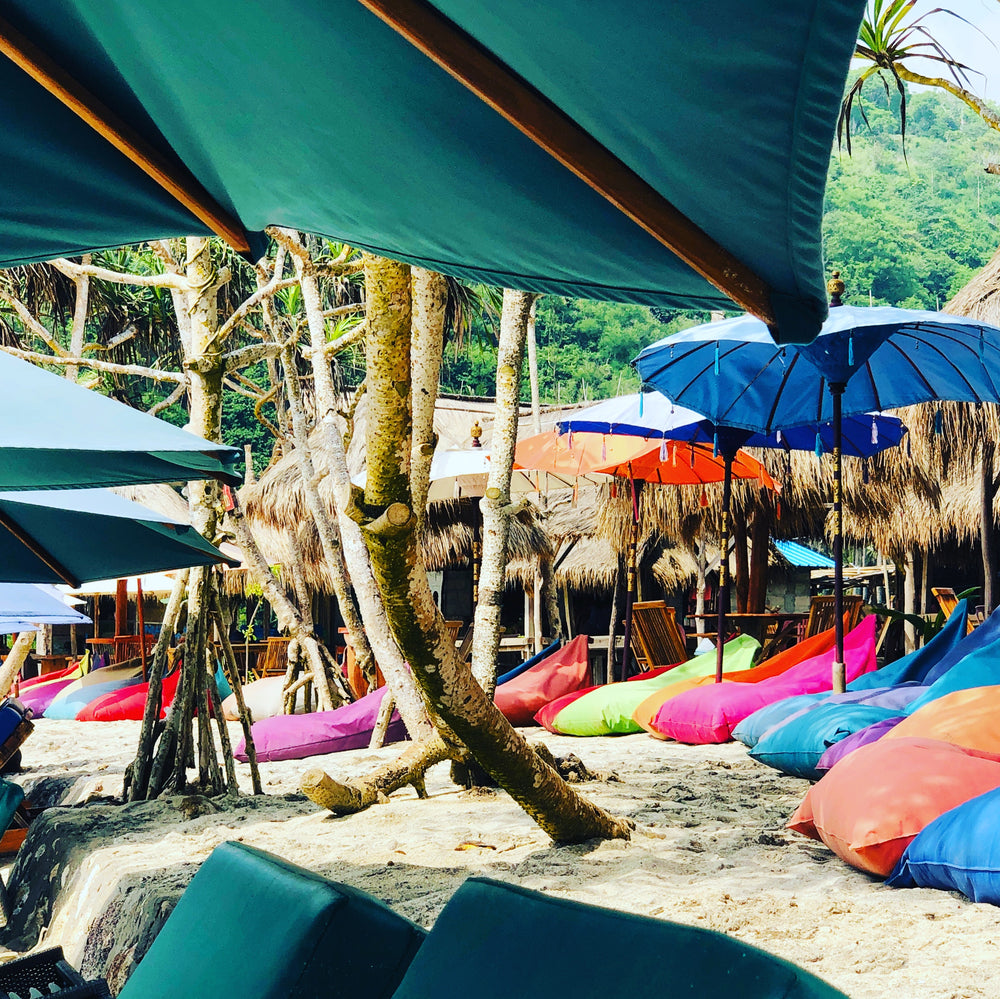 colourful bean bags on a beach under blue shades and trees