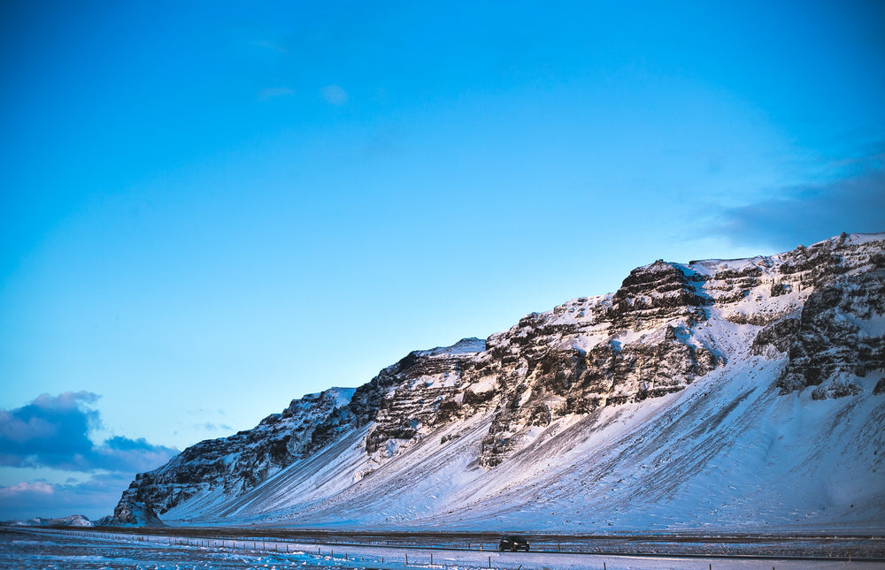 compact car drives past iceland hill