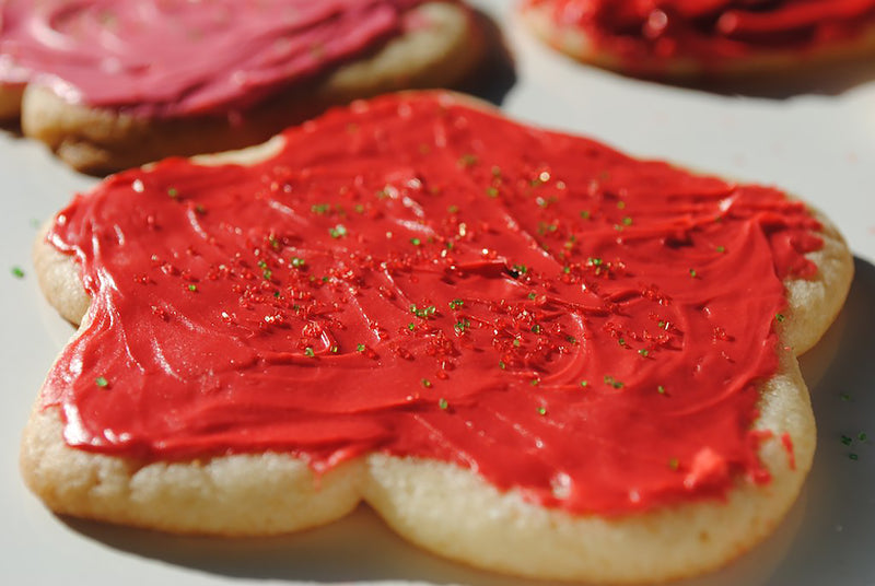 biscuit avec glaçage rouge et pépites vertes et rouges - une assiette avec quelques biscuits recouverts de glaçage rouge