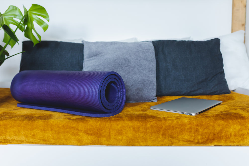 couch with a purple yoga mat and silver laptop