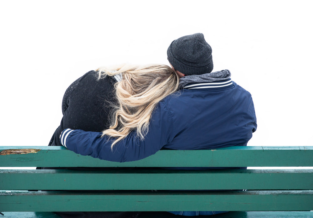 couple cuddles on a park bench