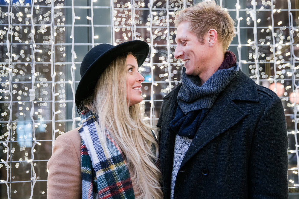 couple gazing in front of holiday lights