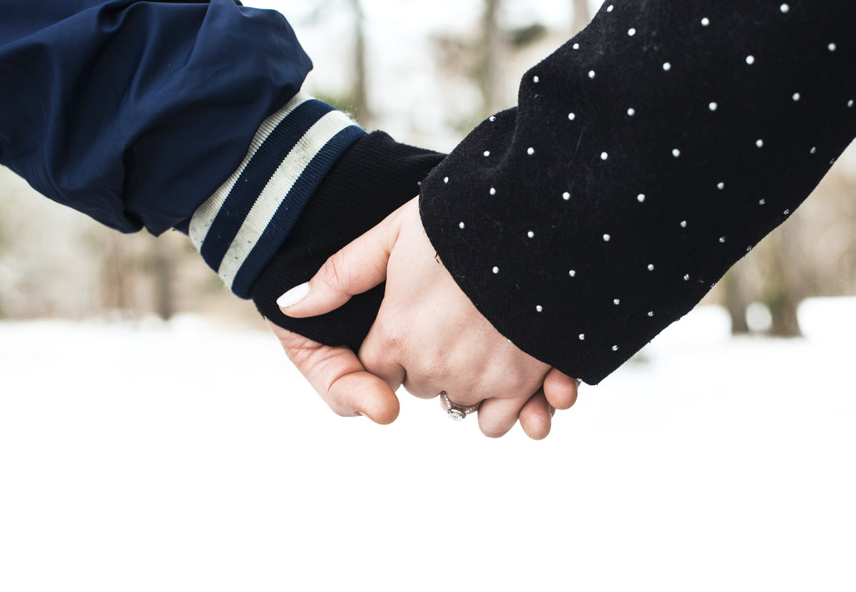 couple hold hands in snow