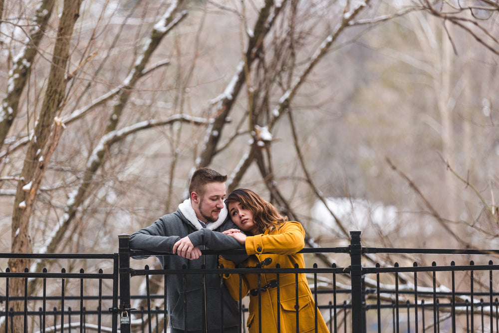 couple holds each other sadly against a frosty gate