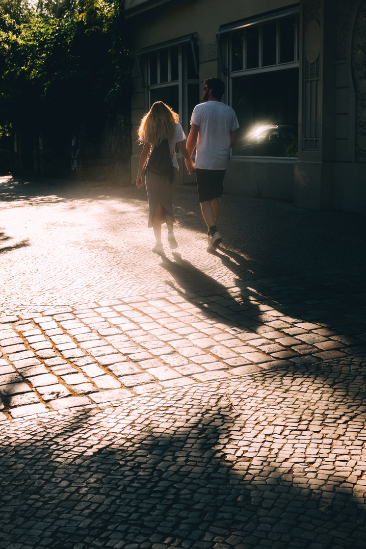 Couple Holds Hands And Walks On Stone Sidewalk