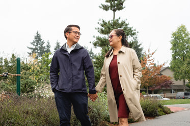 couple holds hands as they walk through park