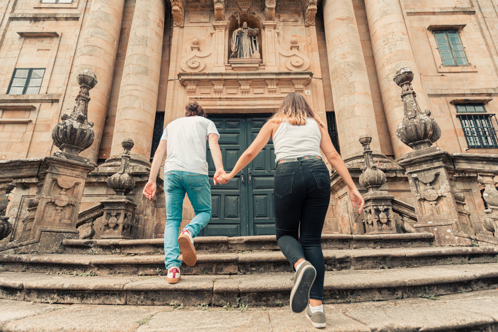 couple holds hands walking up stone steps