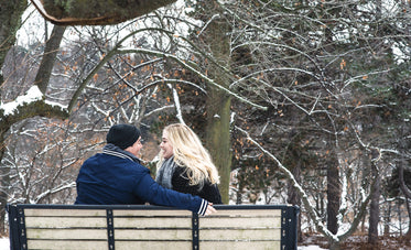 couple laughing over in-jokes on cold park bench