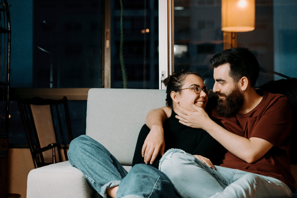 couple on sits on a couch and looks into their eyes