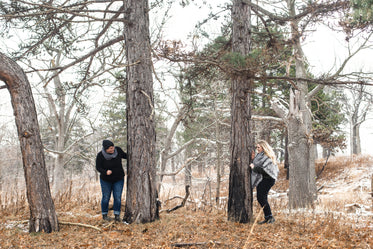 couple playing peek-a-boo behind trees