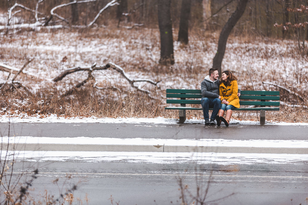 couple shares a smile on a bench by a frosty road