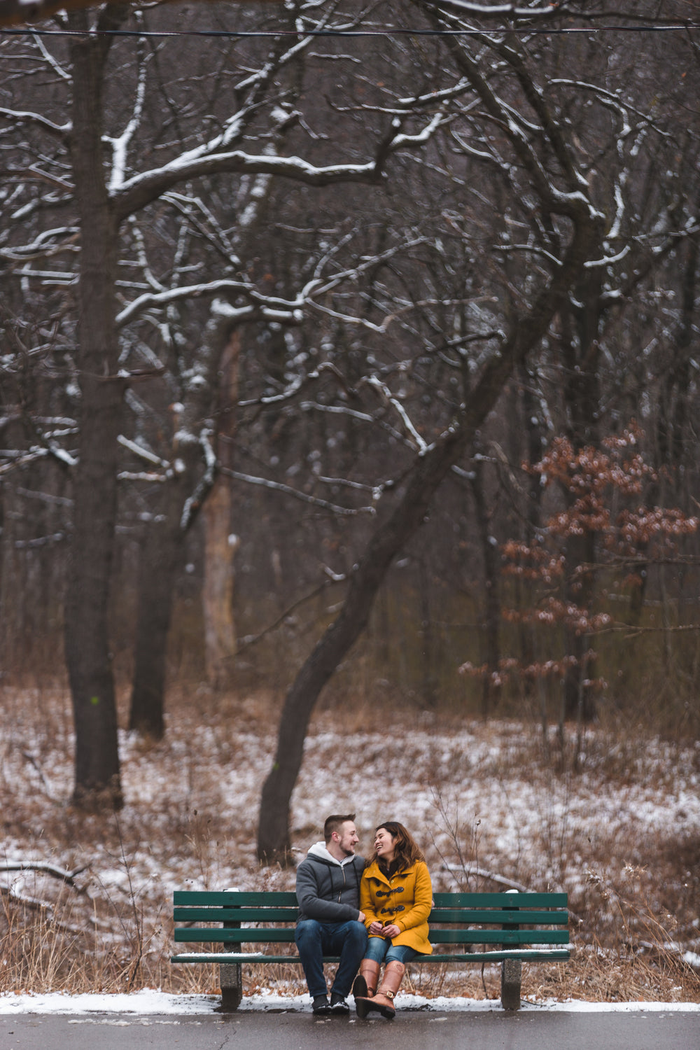 couple shares a warm laugh on a park bench in the winter