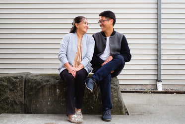 couple smiles and sits on stone ledge