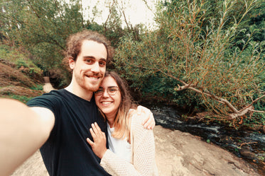 couple stands by a river and take a selfie