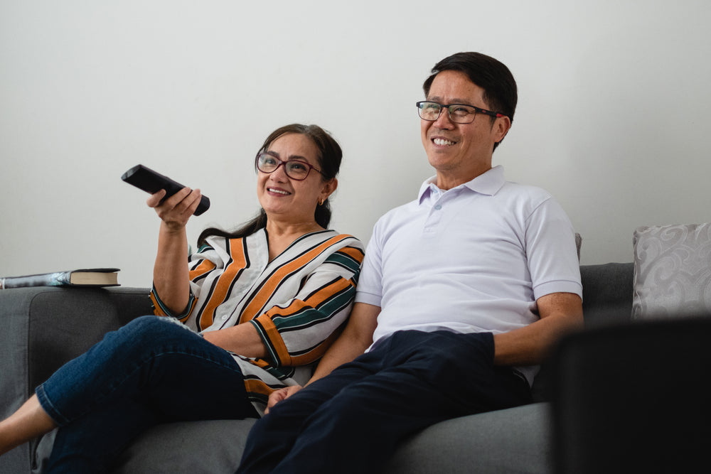 couple watches television on grey couch