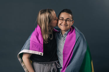 couple wrapped in pride flag kiss