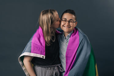 couple wrapped in pride flag kiss
