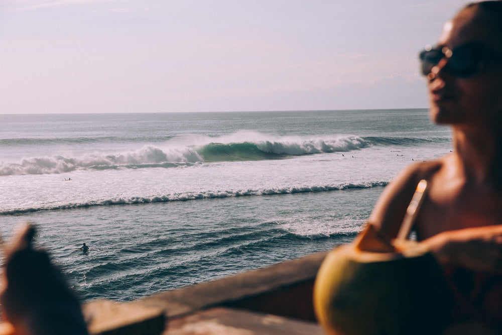 crashing ocean waves in distance behind silhouette of woman