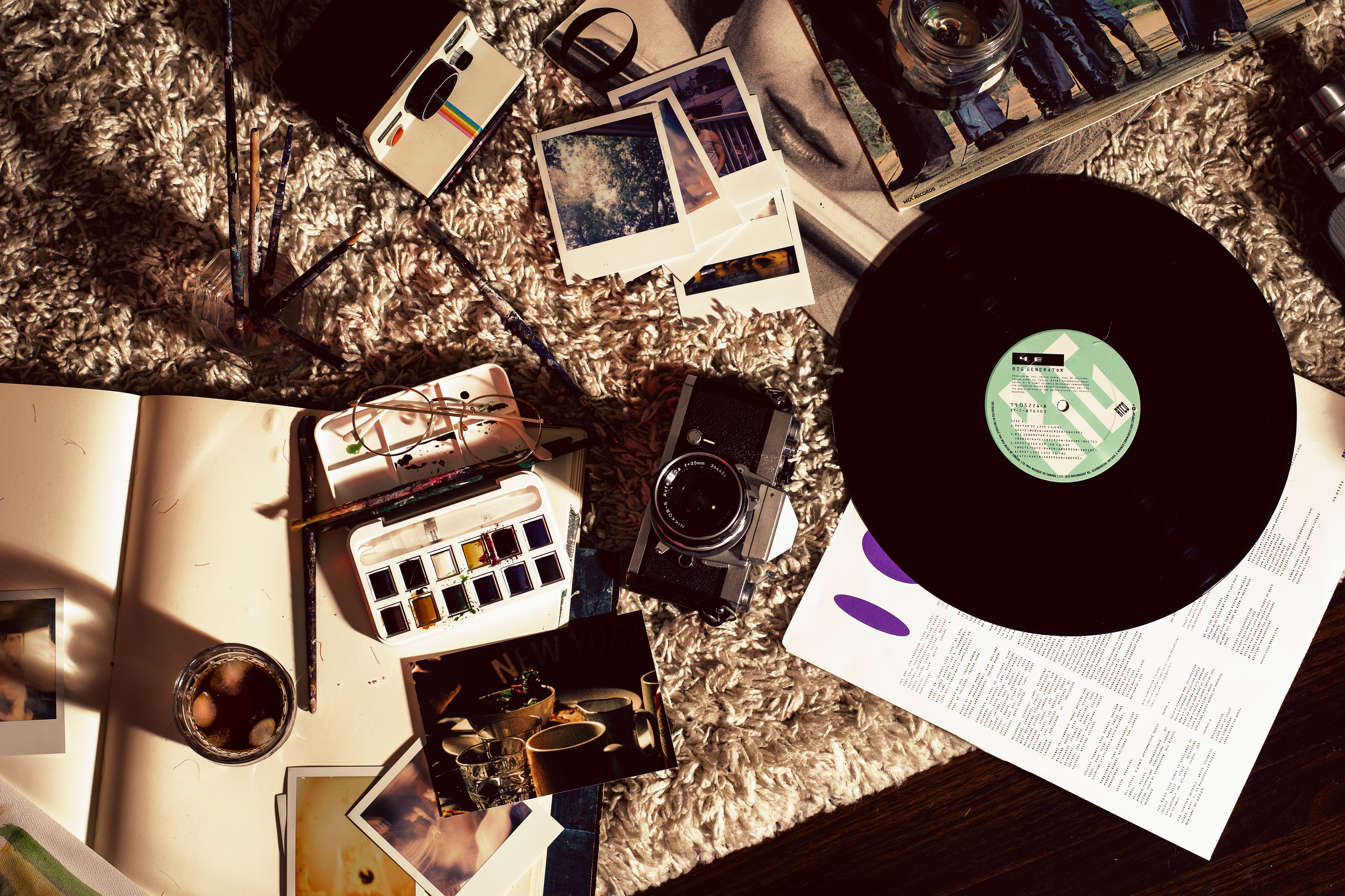 Film camera, sketchbook, instant photographs and a vinyl record arranged for a creative afternoon