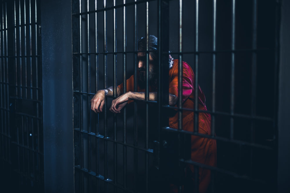 crestfallen prisoner leans on cell door