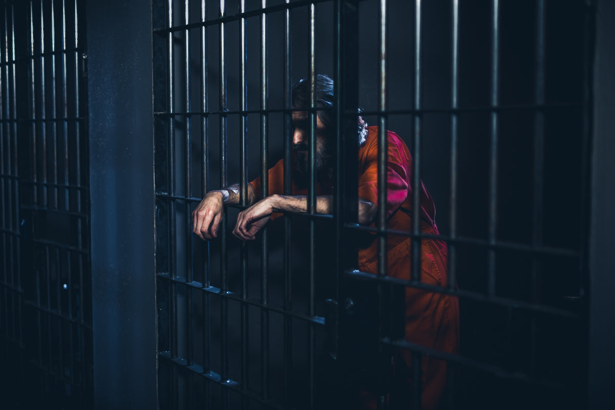 crestfallen prisoner leans on cell door