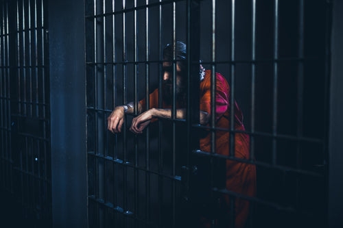 crestfallen prisoner leans on cell door