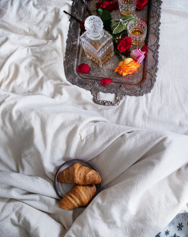 croissants sit close to a tray with roses and a decanter