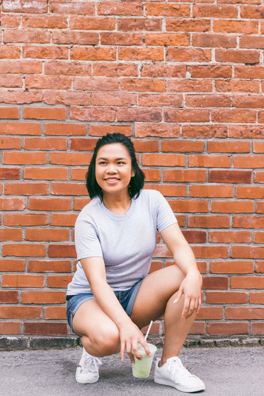 crouching in front of brick wall