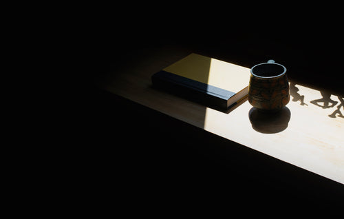 cup and book on a shelf in shadow