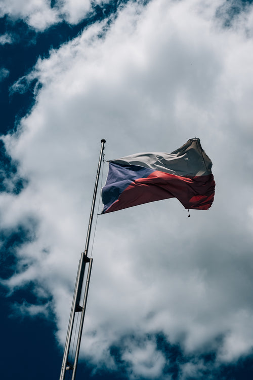 czech flag flies against a cloudy blue sky
