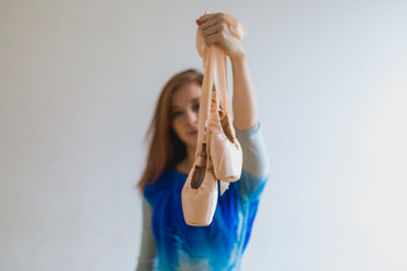 dancer holds out ballet pointe shoes