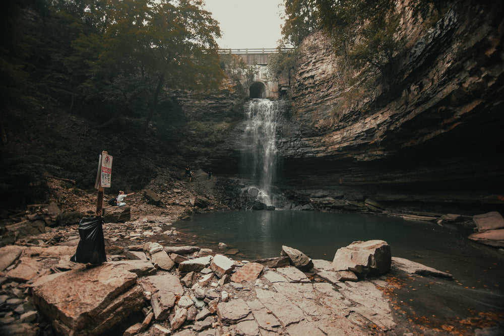 danger sign below rock face with waterfall