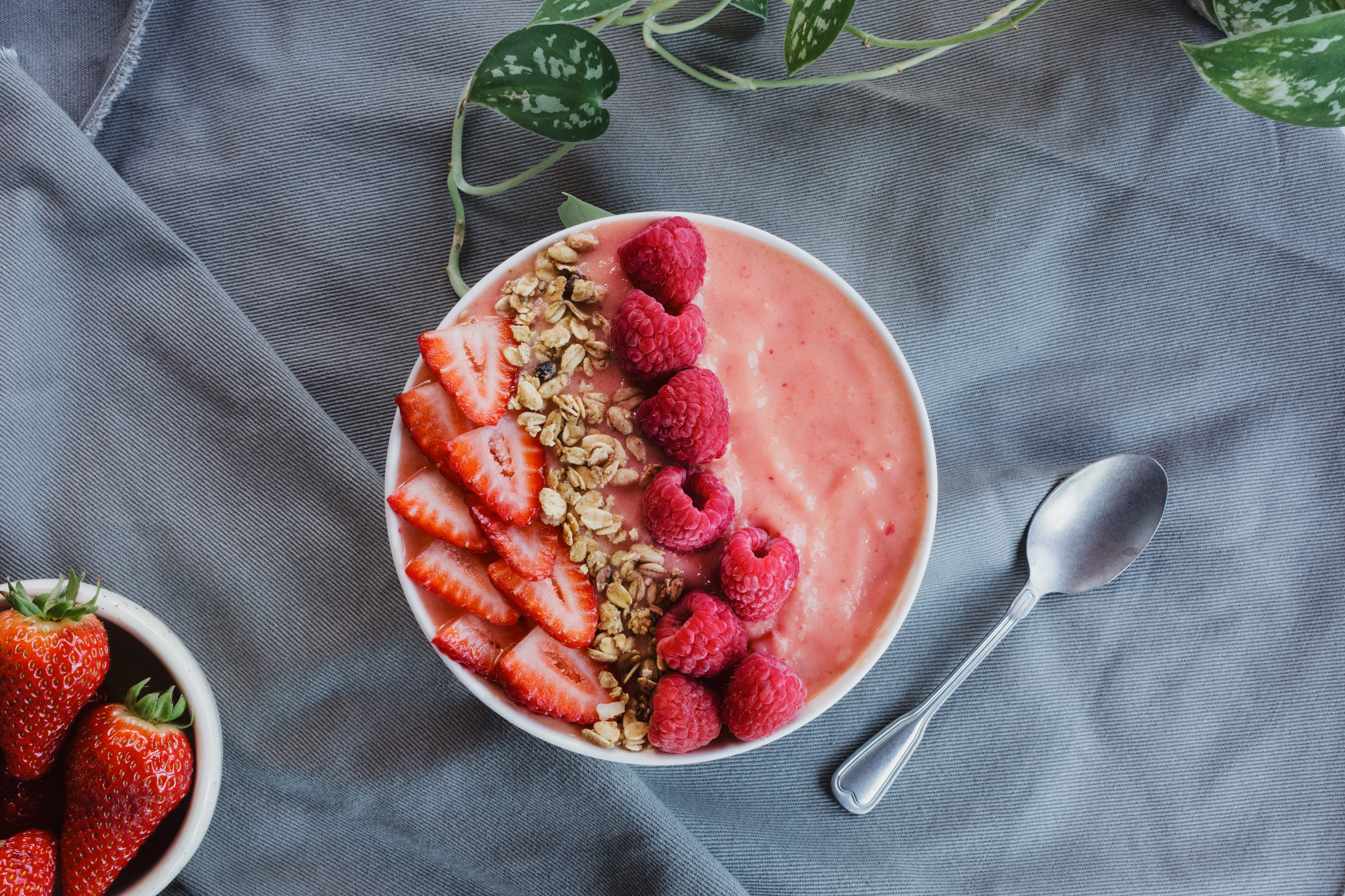 Tigela de smoothie de frutas vermelhas decorada com framboesas e morangos frescos.