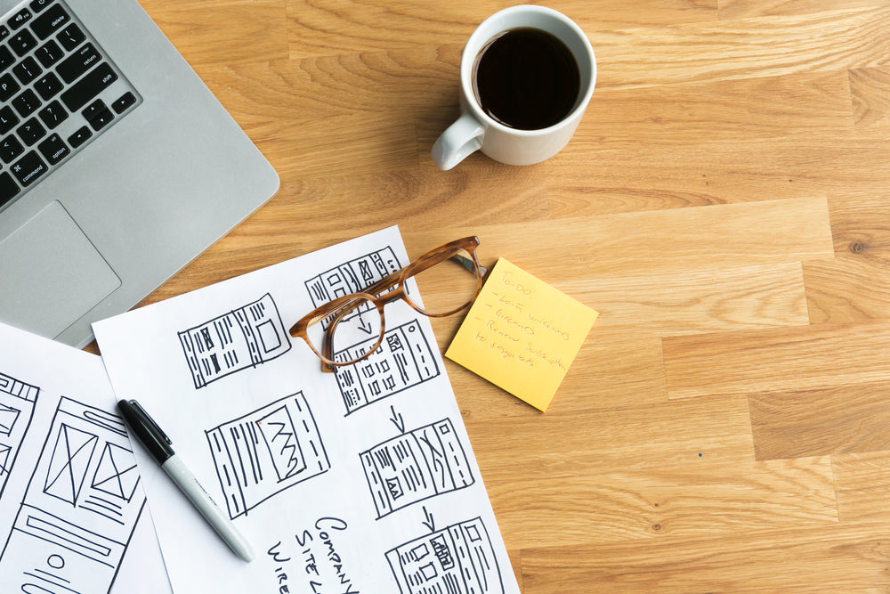 designer's desk with coffee and wireframes